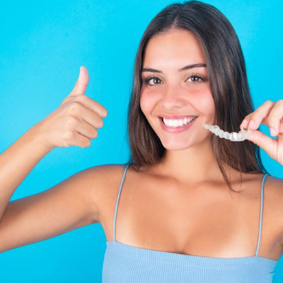 Smiling young woman giving thumbs up for Invisalign
