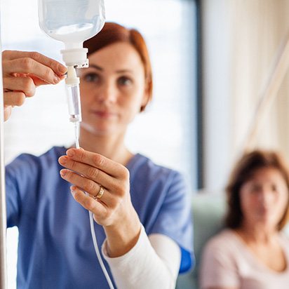 a woman in scrubs adjusting IV medication for a patient