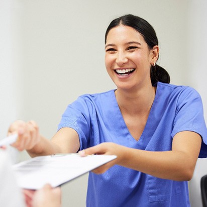 Woman smiling while handing patient form