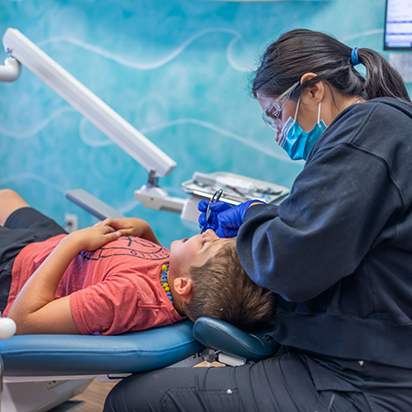 Dental team member giving a child a dental cleaning