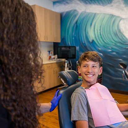 Young boy in dental chair grinning at his dentist