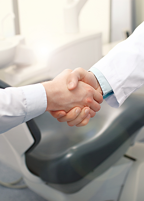 Close up of two people in white lab coats shaking hands