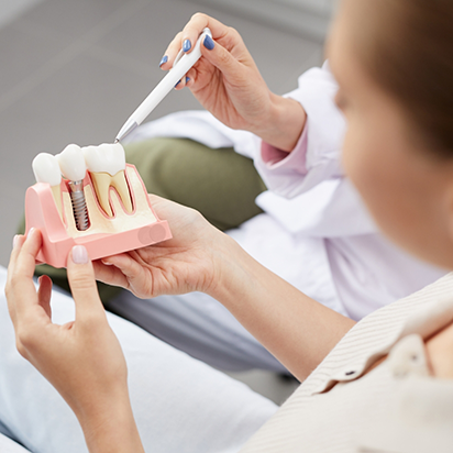 Dentist showing a model of a dental implant to a patient