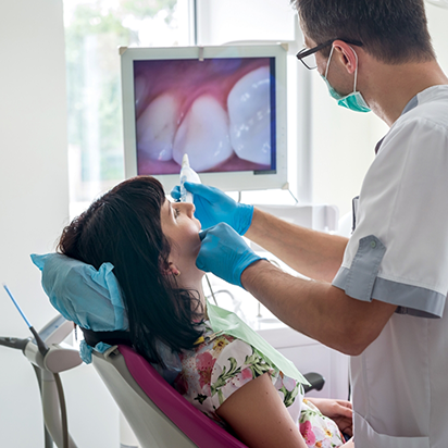 Dentist capturing close up of photos of a patients teeth and looking at them on a chairside monitor