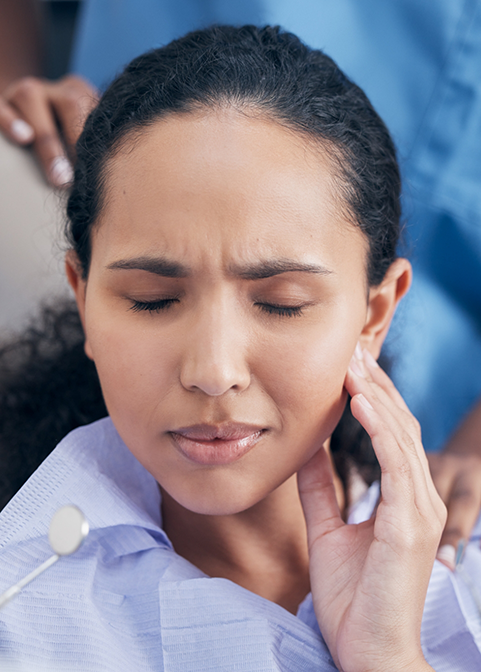 Woman holding her cheek in pain while visiting emergency dentist in Morgan Hill