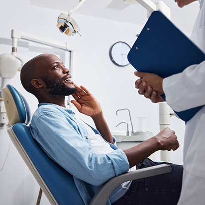 Man sitting in dental chair and talking to his emergency dentist