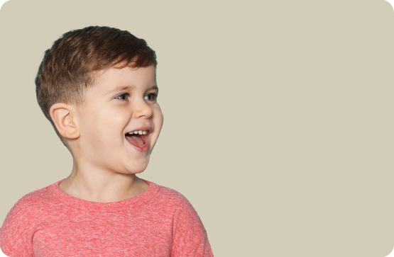 Young boy in light red shirt grinning