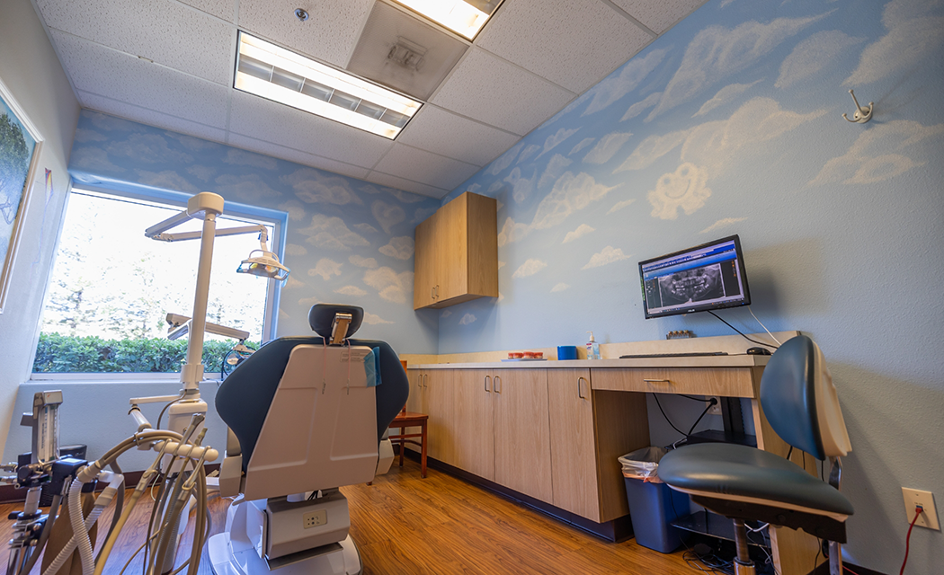 Dental treatment room with walls painted like a pale blue sky with white clouds