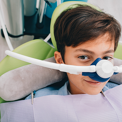 Smiling boy in dental chair with nitrous oxide mask over his nose