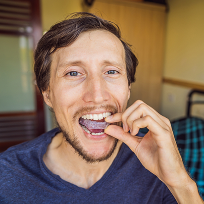 Man placing a clear nightguard over his teeth