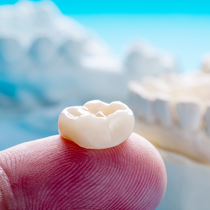 Close up of a dental crown resting on a finger