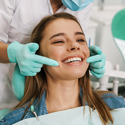 Woman in dental chair grinning with flawless teeth