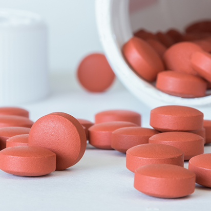 Bottle of red pain pills spilling out onto a table